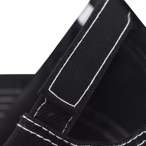 Detailed close-up of adjustable hook and loop strap on black cotton baseball cap with white stitching