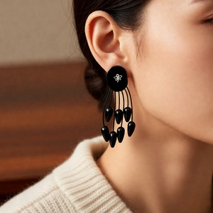 Gros plan de boucles d'oreilles à pompons noirs avec base ovale et perles gouttes