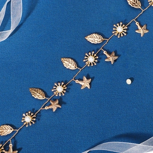 Detail of handmade bridal headband with gold stars, leaves, and pearls on blue fabric