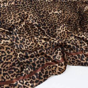Detailed view of leopard print silk satin scarf featuring glossy texture and brown borders