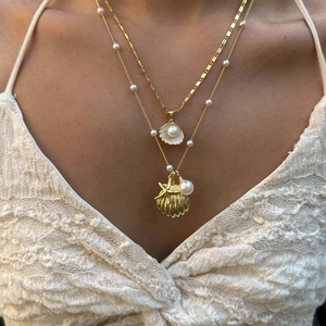 Collana multistrato dorata con conchiglie e perle indossata da una modella femminile