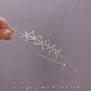Detailed view of a gold star headband with sparkling crystals on a soft purple backdrop