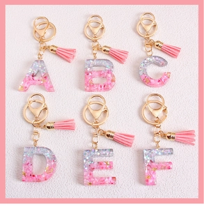 Detailed shot of pink glitter resin A-F alphabet keychains with gold foil and tassels