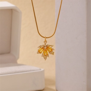 Golden maple leaf pendant necklace with yellow gems and snake chain on jewelry box