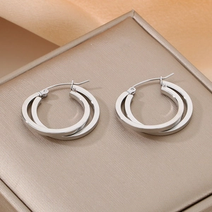 Close-up of silver criss-cross double hoop earrings on a beige textured display box