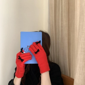 Detail view of red knit gloves featuring cute black bows and soft warm texture