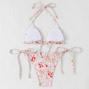 Detail of floral string bikini set with halter top and side-tie bottoms on white plush fabric