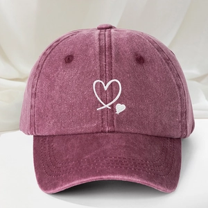 Close-up of double white heart embroidery on a vintage washed pink baseball cap
