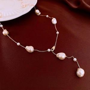 Baroque irregular pearl necklace with gold plated chain on deep red velvet background