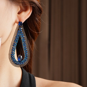 Detailed close-up of blue teardrop earrings featuring rhinestones and hollow mesh design