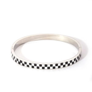 Detailed macro view of the silver stainless steel bangle with black and white checkerboard enamel