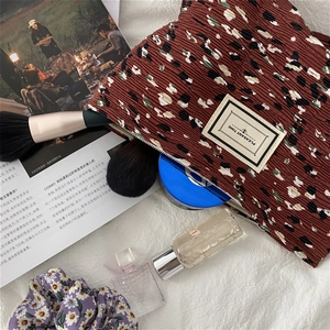 Flat lay of brown pleated floral makeup bag with Pleasant Time label and cosmetic accessories