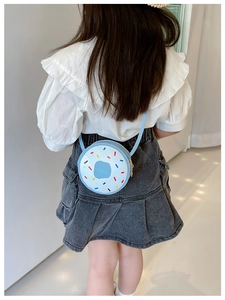 Rear view of child wearing a light blue donut-shaped crossbody bag with colorful dots