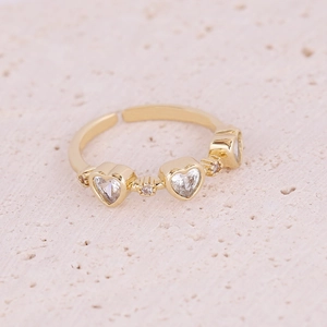 Macro shot of gold adjustable ring featuring three sparkling heart-shaped zircons