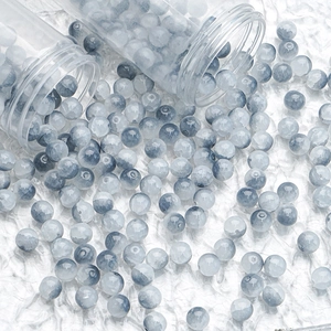 Macro shot of 10mm blue-grey cracked glass beads spilling from glass tubes for DIY jewelry