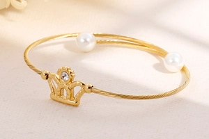 Detail of gold crown bracelet featuring white pearls and a sparkling rhinestone