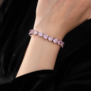 Close-up of pink round-cut zircon tennis bracelet with silver-tone prong setting on wrist