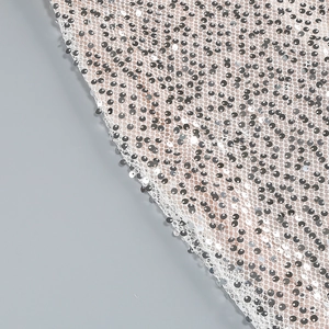 Macro view of silver sequin embroidery on white mesh fabric for evening dresses