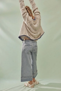 Detailansicht der gestreiften Jeans mit weitem Bein und der Textur des Strickoberteils