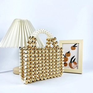 Detailed close-up of handmade beaded handbag with gold beads and white pearl handle