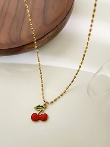Detailansicht einer Kirsch-Halskette mit roten Früchten und goldener Perlenkette