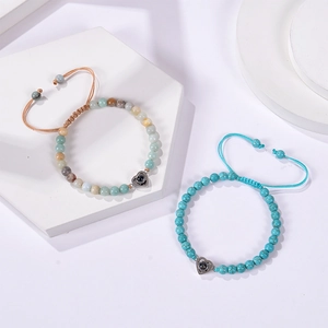 Detail of pink zebra stone and turquoise beaded bracelets with heart projection charms