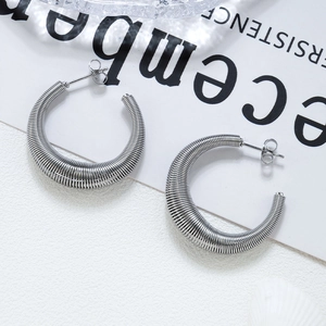 Silver C-shaped spring earrings with spiral texture on a minimalist background