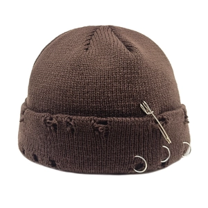 Detail of distressed dark brown knit beanie with silver rings and safety pin accents