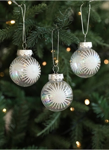 Close-up of clear Christmas balls with white frosted star patterns on a tree