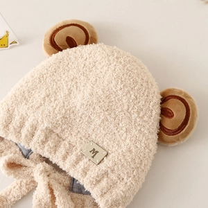Detailed macro view of beige faux shearling baby hat with cute bear ears and M badge