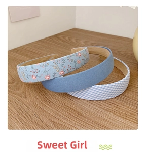 Detailed view of floral and plaid fabric headbands set on a rustic wooden texture background