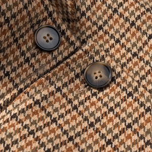 Close-up of houndstooth wool fabric texture and tortoiseshell buttons on short coat