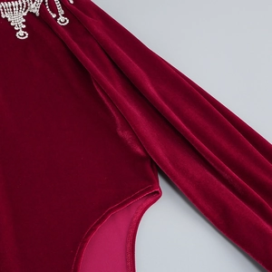Macro detail of wine red velvet fabric with glittering silver rhinestone fringe trim