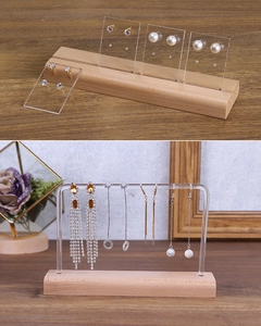 Detailed view of acrylic earring organizers with solid wood bases on a wooden table