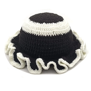 Dettaglio di cappello pescatore a maglia con bordo a balze bianco e nero