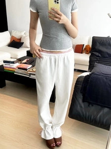 Detail showing pink lace trim and white drawstring on white high-waist joggers