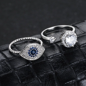 Primer plano de anillo giratorio plateado y anillo mal de ojo con piedras azules