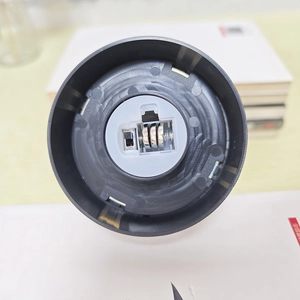 Detail view of the black plastic circular base with an open battery compartment