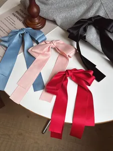 Détails de quatre pinces à cheveux en satin avec de longs rubans sur une surface blanche