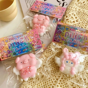 Close-up of three soft pink pig and character squishy toys with pearl chains in packaging