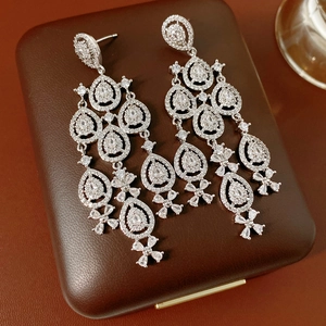 Makroaufnahme von Silber-Quastenohrringen mit Zirkon-Wassertropfen-Blumendesign auf Leder