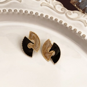 Close-up of vintage flower earrings with black and beige marble enamel in a ceramic dish