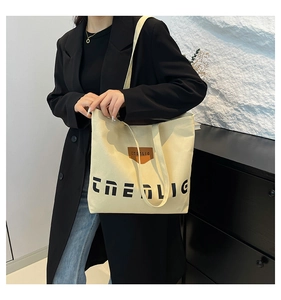 Detailed view of off-white canvas tote bag with black print and leather logo accent