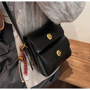 Detail of vintage black leather crossbody bag featuring dual golden twist locks