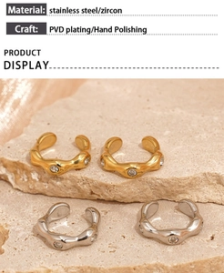 Detail of PVD plated gold and silver zircon ear cuffs on a stone and fabric background
