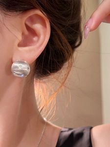 Macro detail of brushed silver dome stud earring featuring tiny star-set cubic zirconia