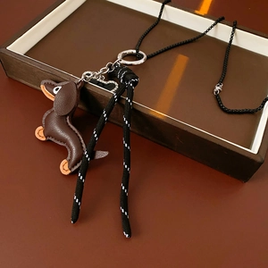 Close-up of leather dachshund pendant with beaded chain and tassels on a gift box