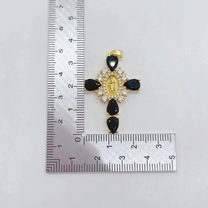 Detailed view of gold cross pendant with blue gems and ruler for size scale