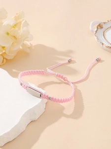 Detail of pink hand-woven adjustable rope bracelet with a polished silver metal plate