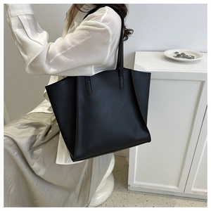 Fashionable black large capacity PU leather tote bag worn by a model in a white outfit